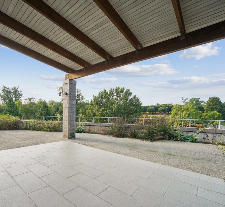 View under a patio covered terrace with trees in the background.