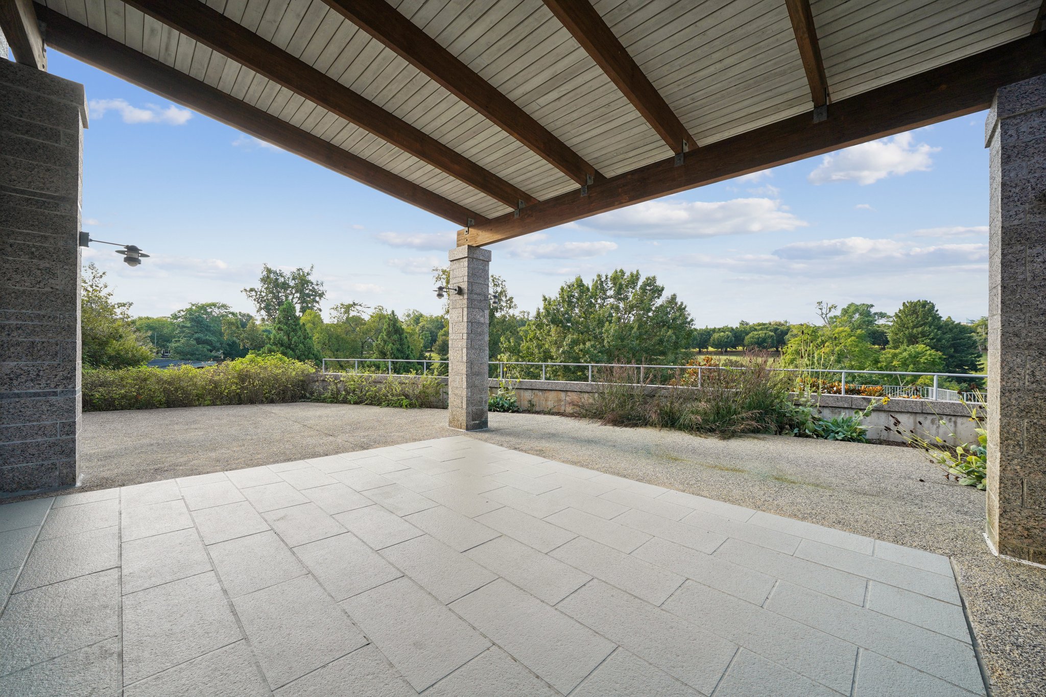View under a patio covered terrace with trees in the background.