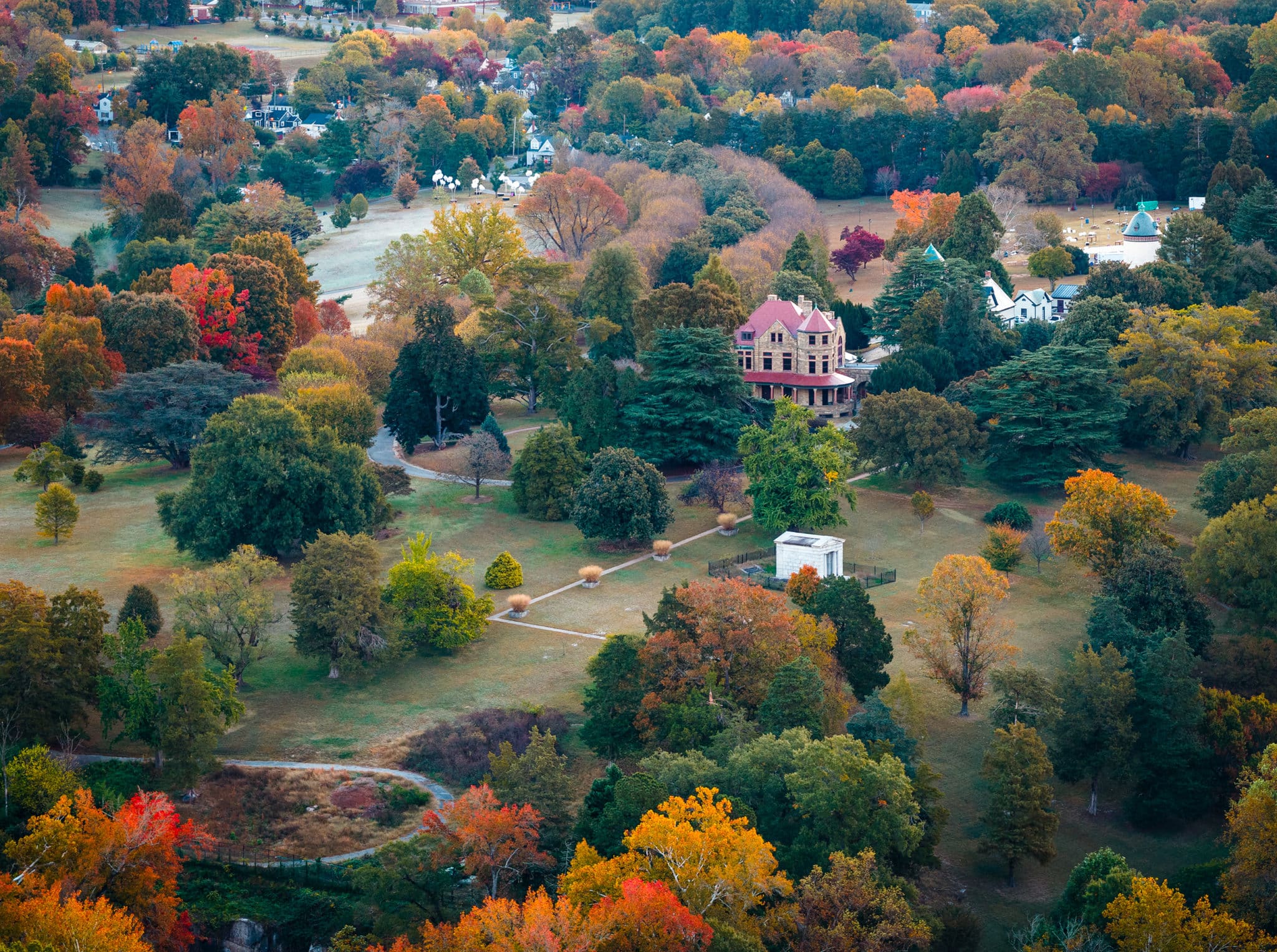 Aerial photo of Maymont grounds during fall with fall foliage throughout the trees. The Maymont Mansion is in view with a newly renovated red slate roof.