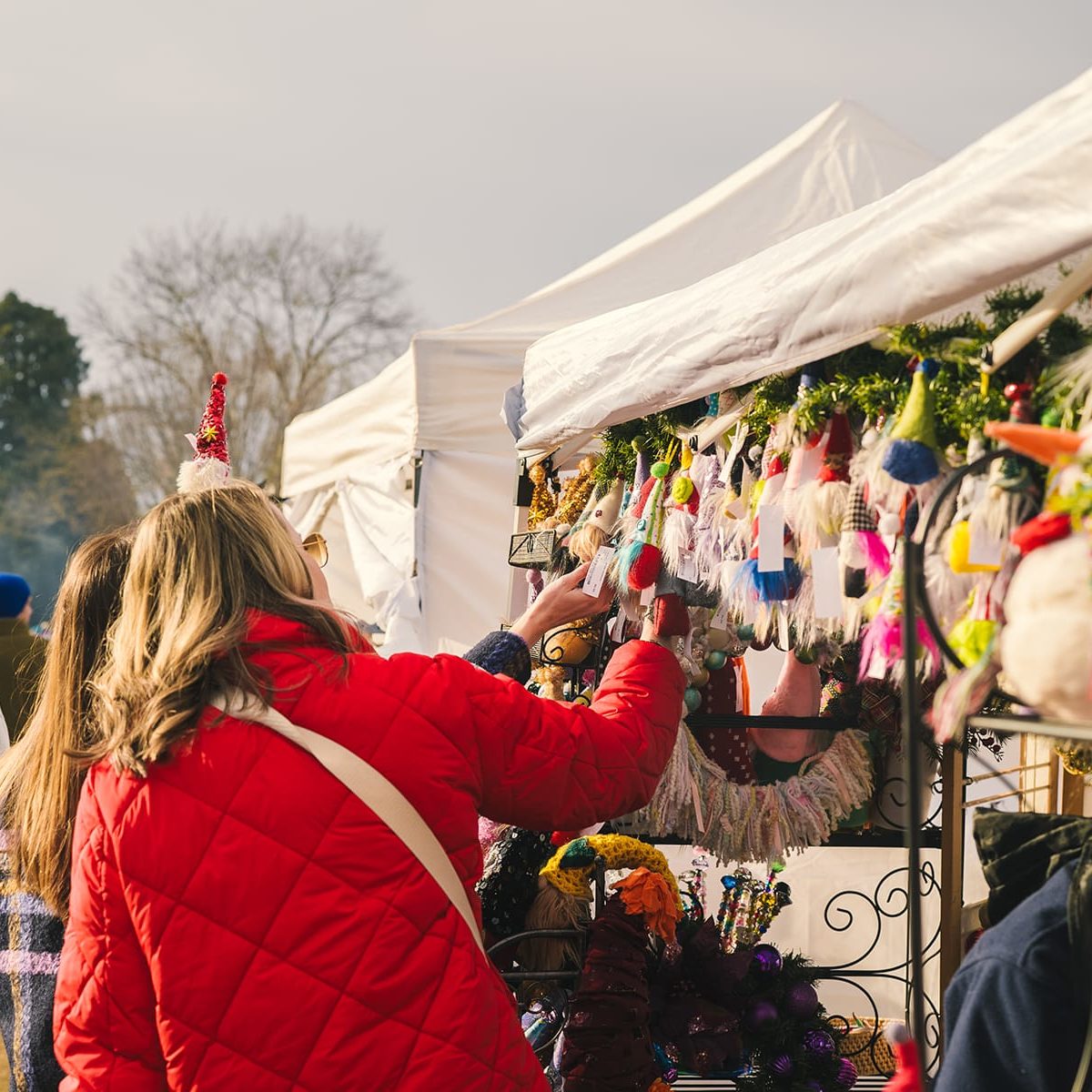 People looking at a vendor tent full of winter/holiday themed goods